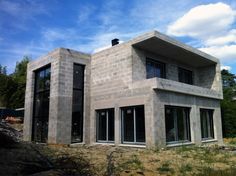 a house that is made out of concrete and has windows on each side, with grass in the foreground