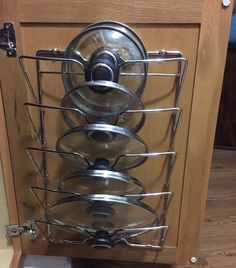 an open dish rack with pots and pans on it in a kitchen cabinet door