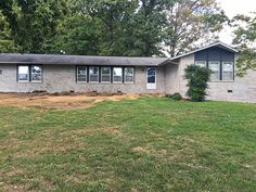 a house that is in the middle of a field with grass and trees around it