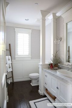 a bathroom with white fixtures and wood floors