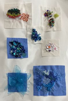 several different types of bead work are displayed on a white tablecloth with blue squares