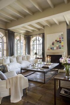 a living room filled with white furniture and lots of windows on the side of it