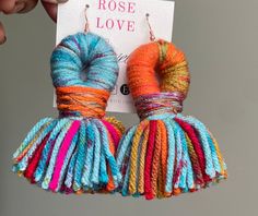 a pair of multicolored yarn wrapped earrings hanging from the back of a card