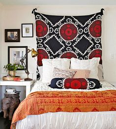 a bed with an orange and black bedspread on it's headboard