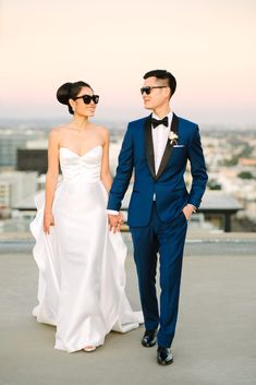 a bride and groom standing on top of a roof with the city in the background