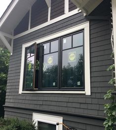 a bicycle parked in front of a gray house with white trim on the window sill