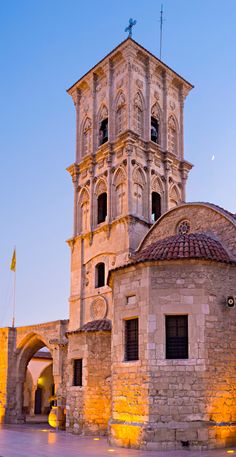 an old stone building with a clock on the front and side of it at dusk