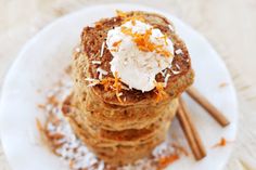 a stack of pancakes topped with whipped cream and orange zest on a white plate