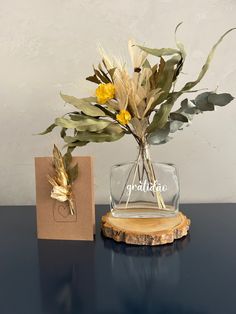 a vase filled with flowers sitting on top of a table next to a small card