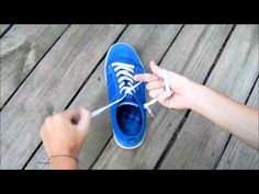 a person is tying the laces on a pair of blue tennis shoes with a toothbrush