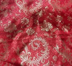 red and gold brocaded fabric with white flowers