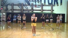 a group of girls standing on top of a basketball court holding microphones in front of them