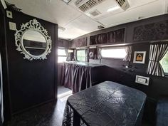 the interior of an rv with black walls and curtains