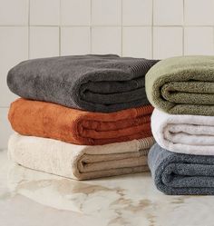 towels stacked on top of each other in front of a white tiled wall and counter