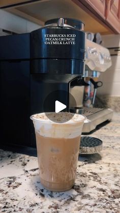 an iced drink is sitting on the counter in front of a coffee maker and espresso machine