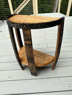 a wooden table sitting on top of a wooden floor next to a railing and trees