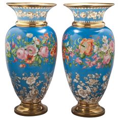 two blue vases with flowers painted on them sitting side by side in front of a gray background