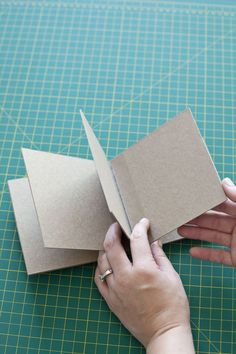 someone is cutting out an origami book on a green mat with a pair of scissors