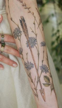 a woman's arm with flowers and leaves on it