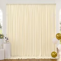 a room with balloons and curtains in the corner, along with two white vases filled with flowers