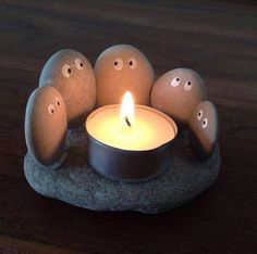 an image of a candle that is in the middle of rocks with faces on it