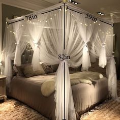 a canopy bed with white drapes and lights on the headboard is in a bedroom