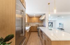 a modern kitchen with stainless steel appliances and wood cabinets, along with marble counter tops