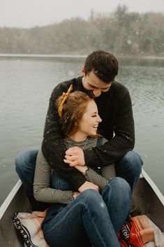 a man and woman sitting in a boat on the water with their arms around each other