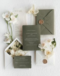 the wedding stationery is laid out on top of each other with flowers and envelopes