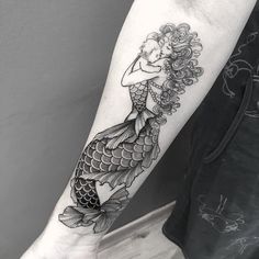 a black and white photo of a woman's arm with a fish tattoo on it