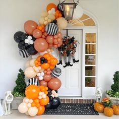 a bunch of balloons that are hanging on the front of a house with pumpkins and other decorations