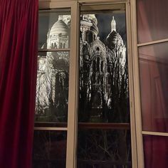 an image of a building seen through a window with red drapes on the windowsill