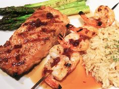 a white plate topped with meat, rice and asparagus next to broccoli