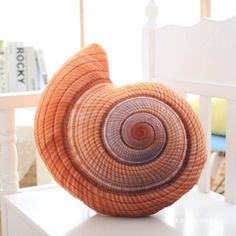 an orange basket sitting on top of a white table next to a chair and bookshelf