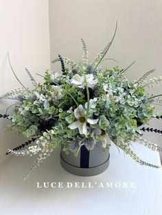 a vase filled with flowers and greenery on top of a table