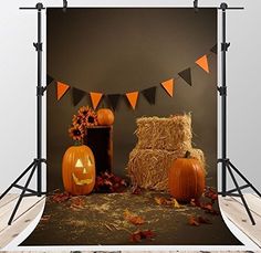 pumpkins and hay bales on a wooden floor in front of a black wall