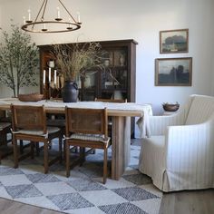 a dining room table with chairs and a potted plant in the center, on top of a checkered rug