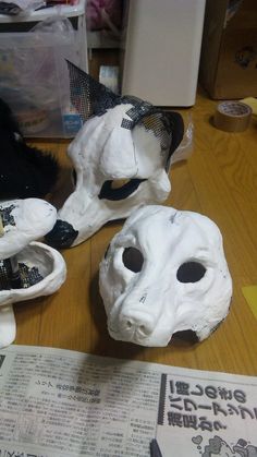 a cat is sitting on the table next to some fake masks