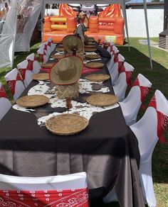 a long table covered in black and red cloths with cowboy hats on it's head