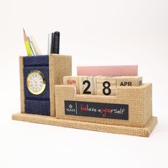 a desk organizer made out of burlap with a clock, calendar and pen holder