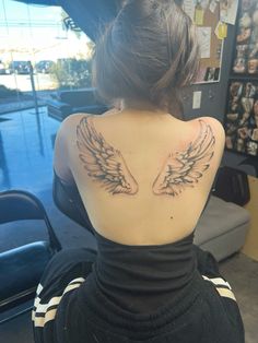 the back of a woman's neck with angel wings on it