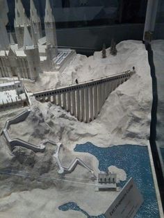 a model of a castle with water and snow surrounding it in a glass display case