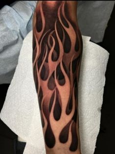 a man's arm with black and grey flames on the inside of his arm