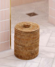 a wicker basket sitting on the floor next to a tiled wall and door way