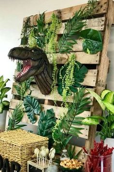 a dinosaur head is mounted on a wooden pallet with plants and other decorations around it