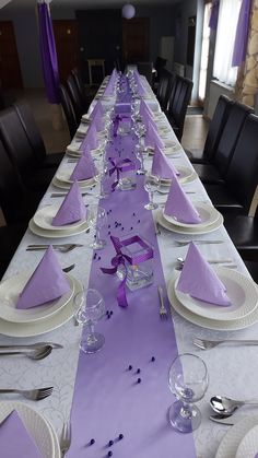 the table is set with purple napkins and place settings for people to sit at