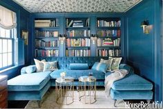 a living room with blue couches and bookshelves