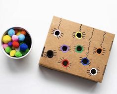 a box filled with colorful pom poms next to a bowl of colored balls