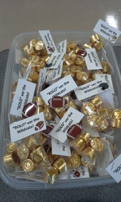 a plastic container filled with lots of gold and chocolate candies on top of a table