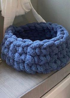 a blue crocheted basket sitting on top of a bed